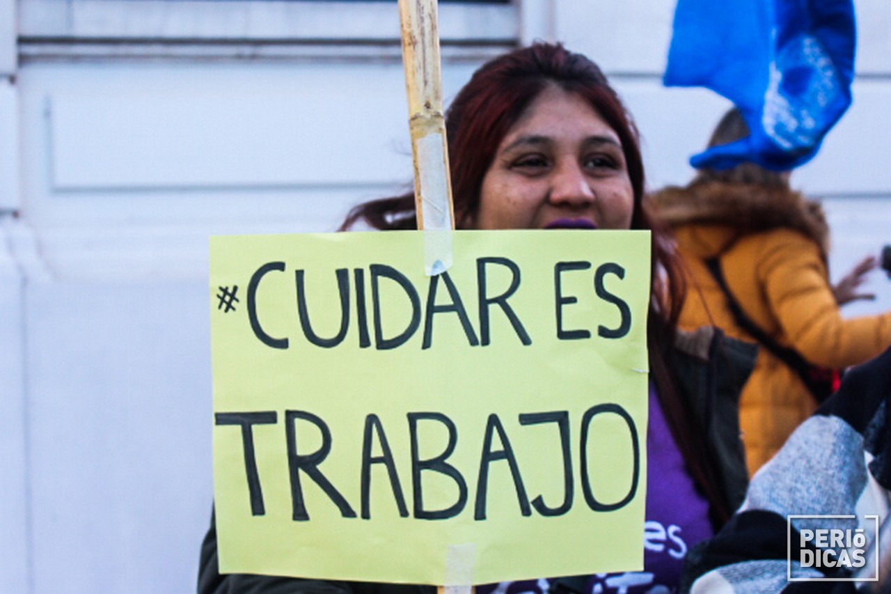 Mujer sostiene un cartel con la leyenda "Cuidar es trabajo"